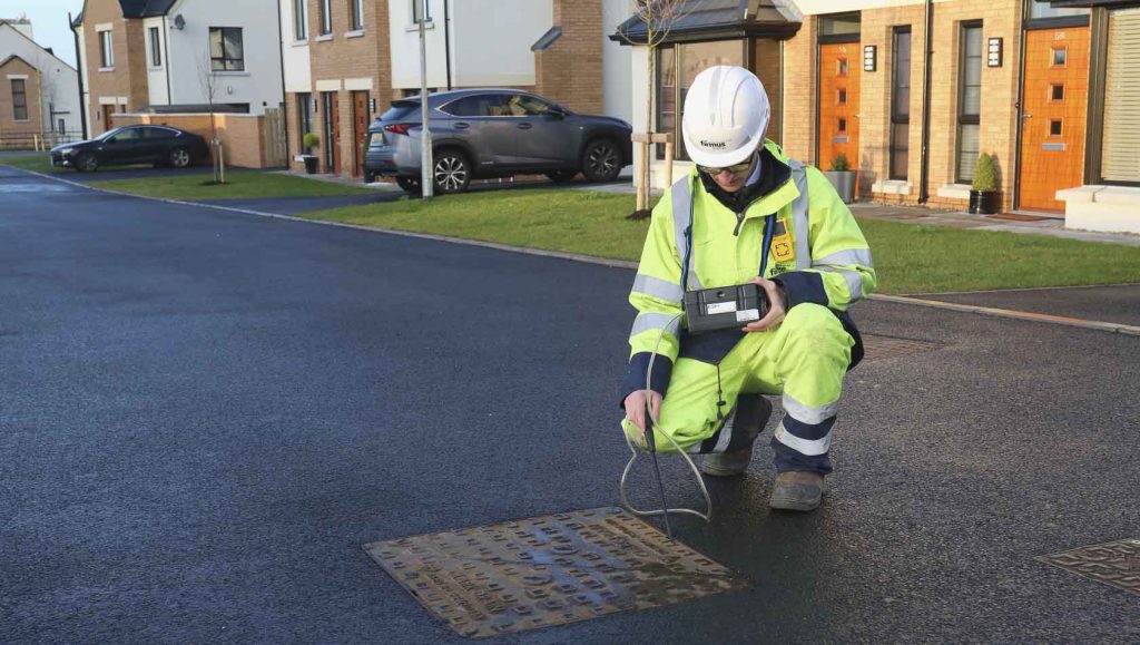 A man in high vis opens a drain cover