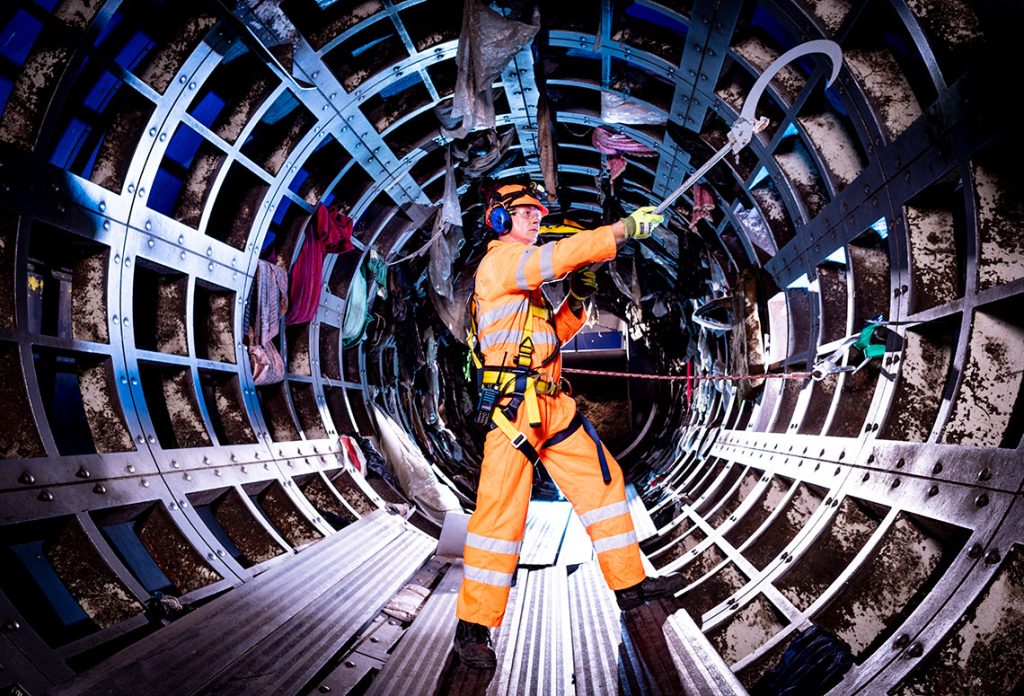 A man working the interior of an underground steel tunnel