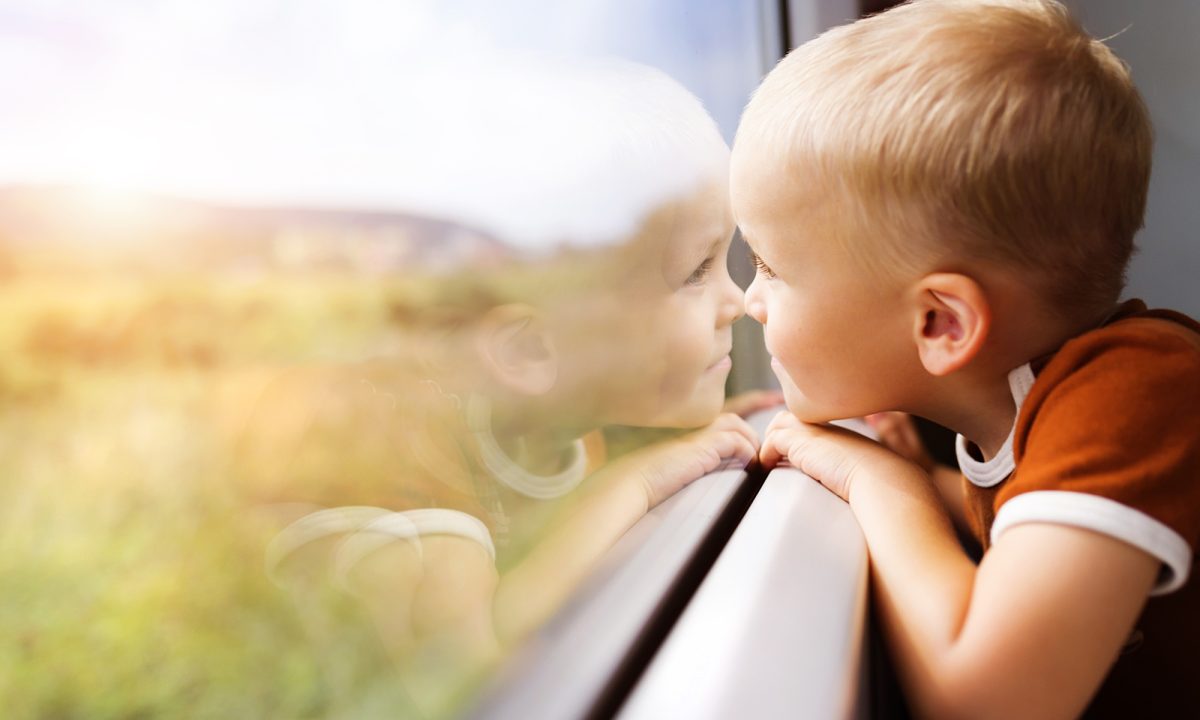 A boy looks out a train window